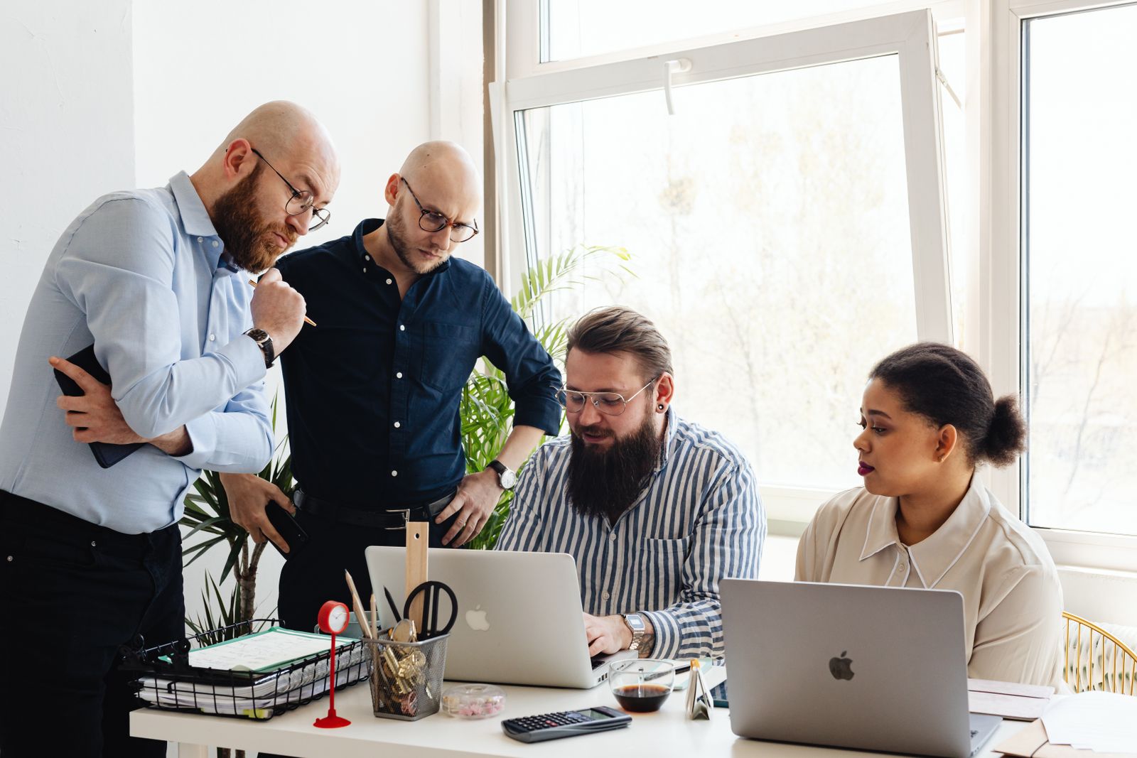 A small team working together around laptops by a bright window