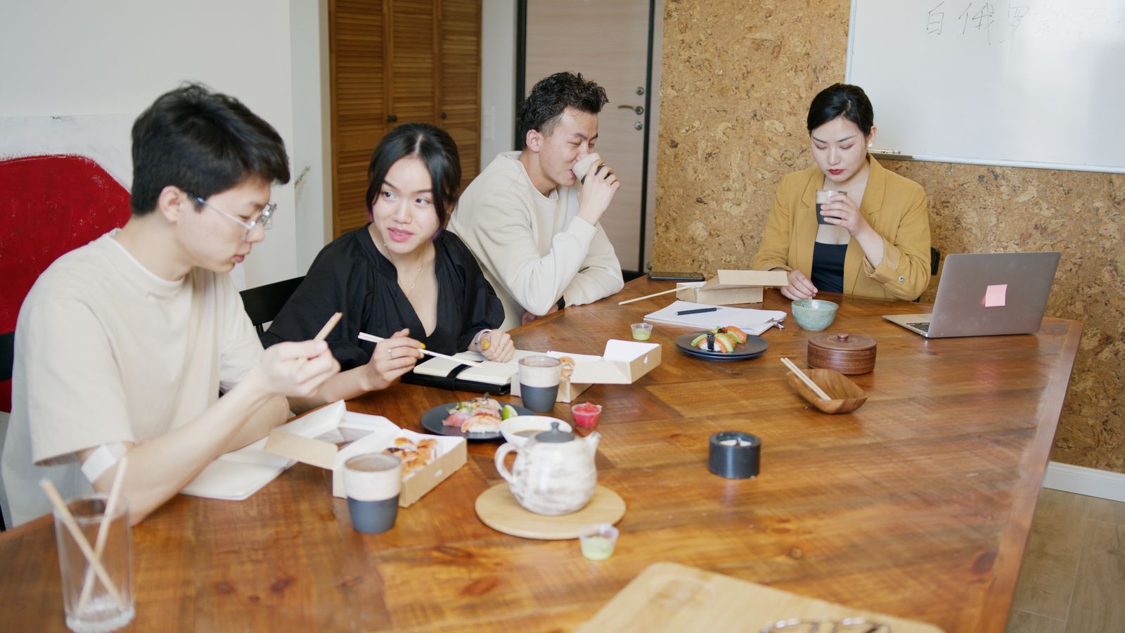 Colleagues sharing lunch around a wooden table in an office