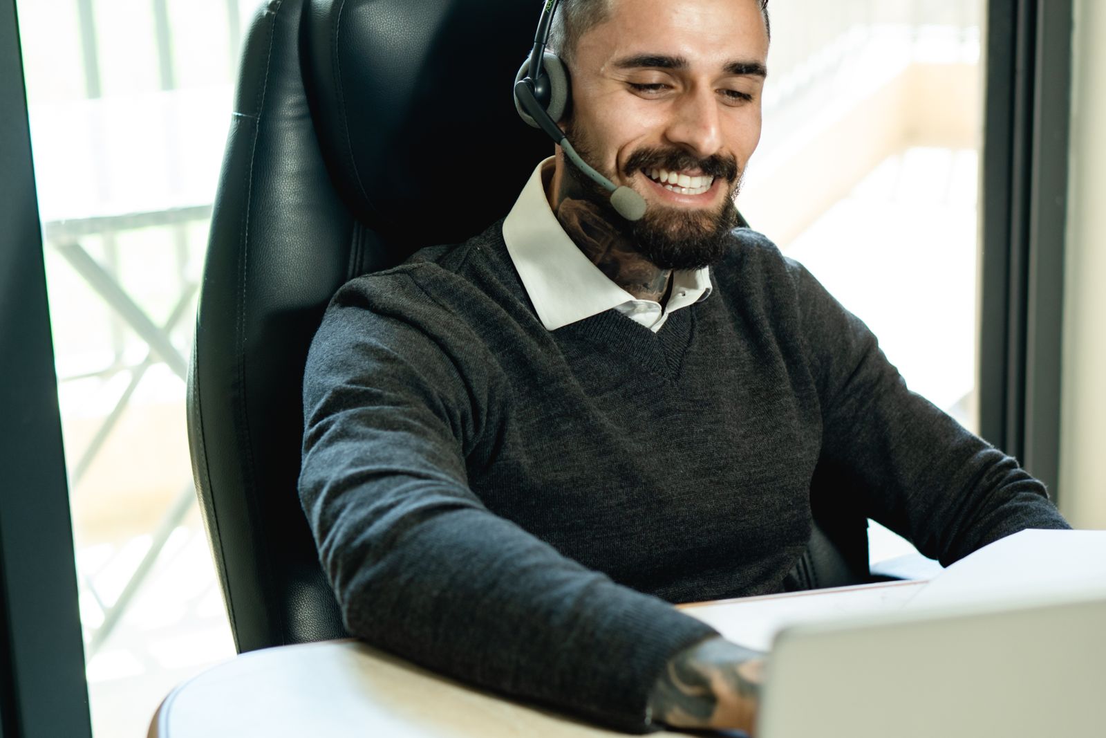 A smiling support person wearing a headset at a laptop