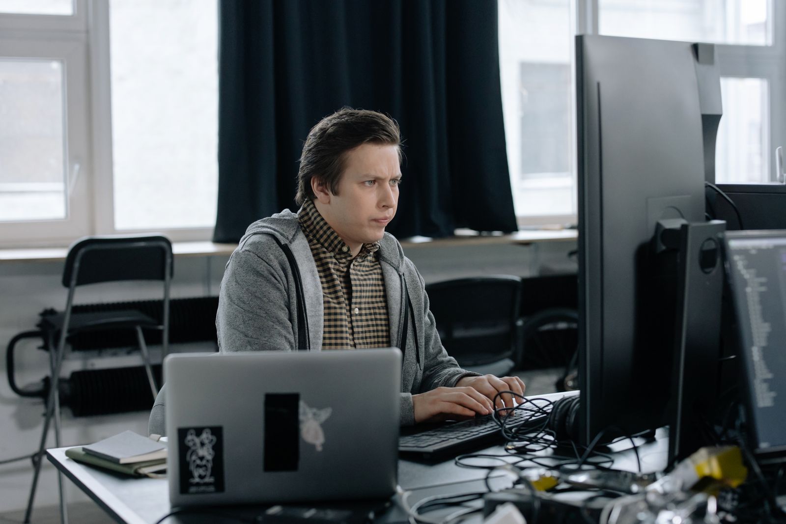 An engineer at a desk with two monitors and a laptop