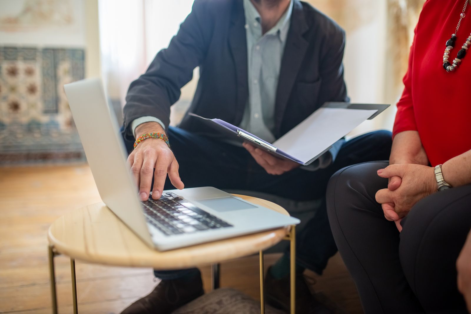 A lawyer going through documents with a client at a laptop