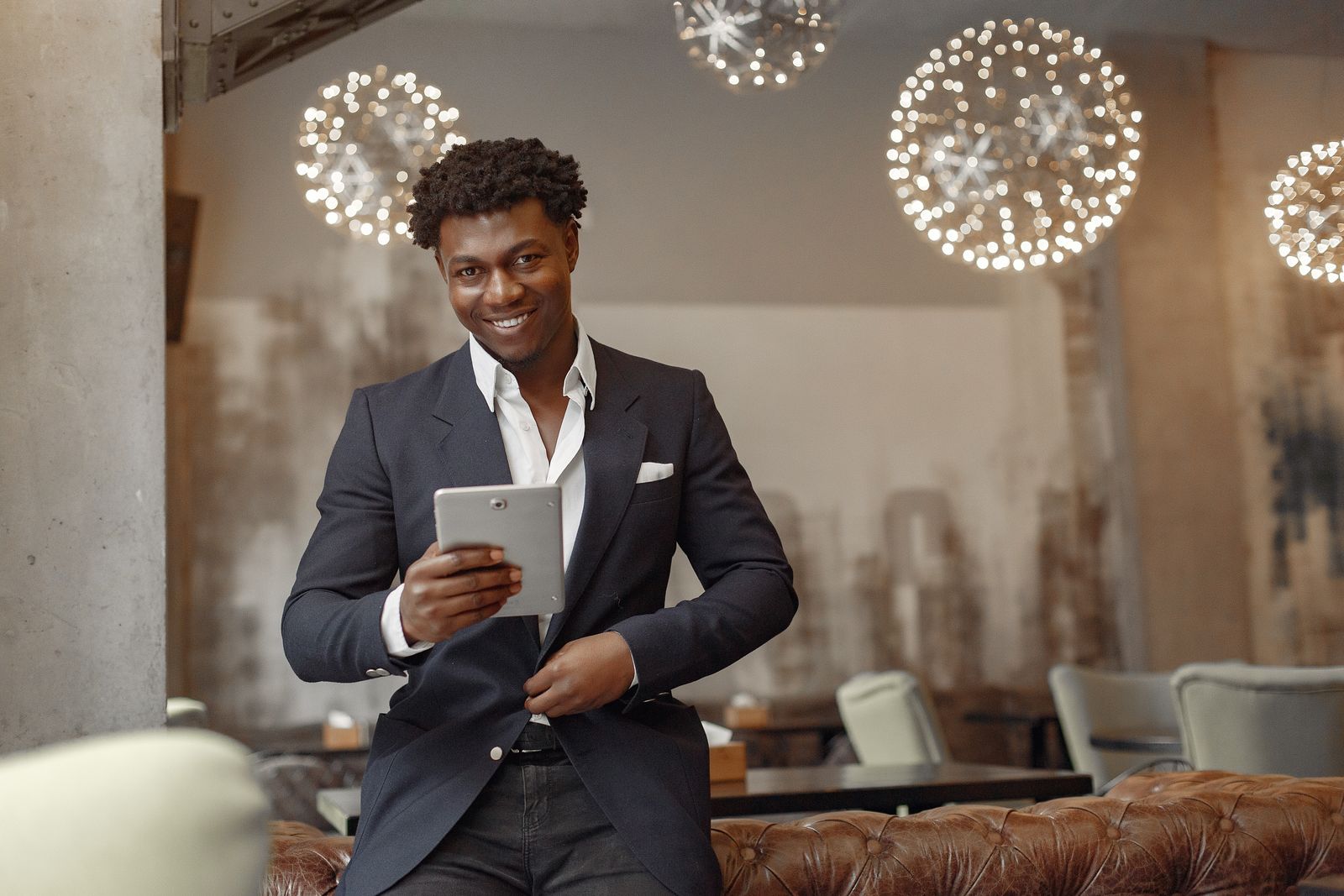 A smiling business owner holding a tablet in a café